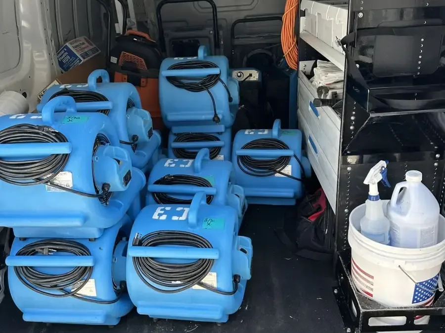 Air movers, a dehumidifier and cleaning supplies packed in the back of a restoration van ready to roll