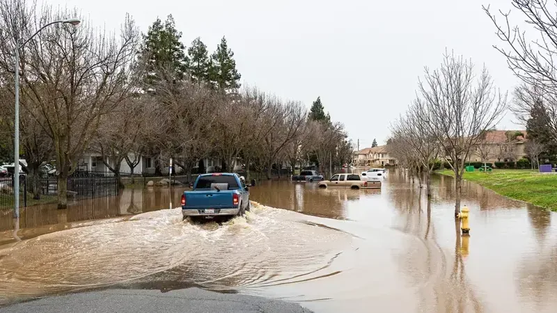 Pickup truck driving through a flooded residential street after a storm